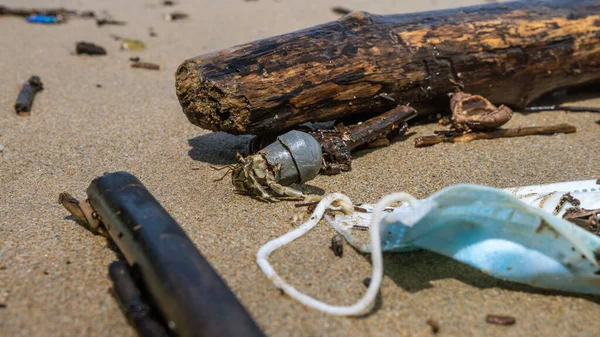 ハーミットカニは 医療廃棄物 マスクゴミゴミの近くにチューブプラスチックを運ぶ コロナウイルスは 19の汚染疾患環境をCovid ビーチの海岸に投げ外科用マスクを使用 — ストック写真