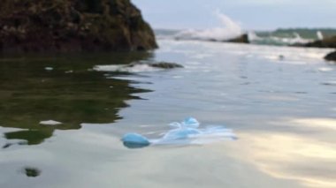 Tıbbi atıkların yavaşlaması plastik eldivenler deniz suyundaki çöpler. Coronavirus covid-19 çevre kirliliği hastalığı. Bir kumsala atılmış mavi eldiven. -Dan.