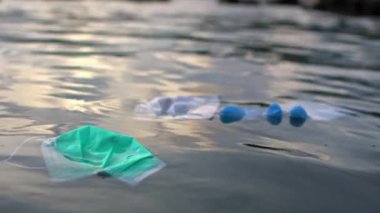 Tıbbi atıkların yavaşlaması, deniz suyundaki çöpleri maskeliyor. Coronavirus covid-19 çevre kirliliği hastalığı. Plaja atılan cerrahi maske ve plastik eldiven kullanılmış.