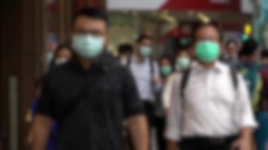 Asyalıların yüz maskesi takıp karşıya geçerken bulanık bakışları yavaş hareket ediyor. Çoğu yaya, kendini koronavirüs enfeksiyonundan korumak için tıbbi maske kullanıyor.