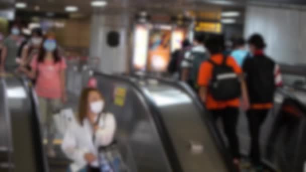 地下鉄の入り口のエスカレーターで感染症に対する保護マスクを身に着けているアジアの人々のぼやけた焦点を当てたビューは 鉄道駅につながる コロナウイルス対策ダン — ストック動画