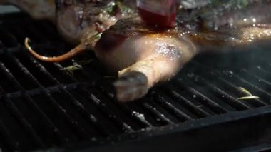Şef barbekü ızgarası için domuz etine leziz sos ve sos koydu. Tatil tatillerinde mangal evinde domuz ızgarası pişirilmiş et. İspanya 'da domuz yavrusu pişiren adam