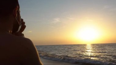 4K, COVID-19 beyaz adam İspanya 'da koronavirüs hastalığını yaymak için yüz maskesi takıyor. Gün batımında SARS-CoV-2 'ye karşı cerrahi maskeli bir adamın portresi.