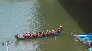 Taipei, Tayvan-08 Haziran 2024: Taipei kürekçisinin yavaş hareketi sakin odaklı küreği kaldırıyor, teknenin altında dalgalanan altın yansımalar.