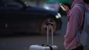 Chengdu, Çin-11 Ekim 2024: Yalnız bir Asyalı kadının Chengdu 'da yumuşak kentsel ışıklar altında telefonunu kontrol etmesi yalnızlık ve dijital bağlantıyı karıştırıyor.