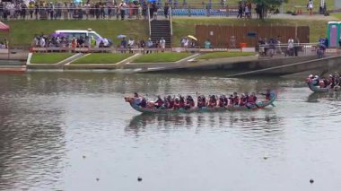 Taipei, Tayvan-08 Haziran 2024: Yavaş hareket eden Taipei kürekçisi kucağında kürekle dinlenirken, sıcak ışıkta, durgun suyun yanında gözleri kapalı.