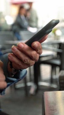 Barda akıllı telefon kullanan beyaz bir kadın, bir bardak aperol kokteyli. İtalyan restoranında cep telefonuna dokun. İnternette sörf yapmak, sosyal ağı kontrol etmek ve cep telefonuna metin yazmak