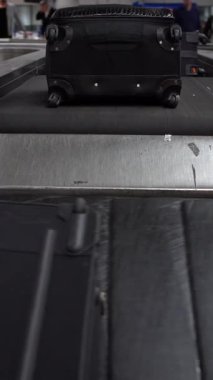 4k, Suitcase on luggage conveyor belt in the baggage claim at arrivals lounge of airport international terminal building. People picking up suitcases and bags in the waiting area. Journey concept