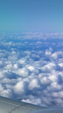 4K, Beautiful clouds from above, as seen through airplane window. Traveling by air. View of traveler in cabin at turbine and plane wing in flight trip with blue sky.