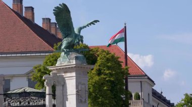 Slow motion of the Hungarian flag with a prominent statue and historic building in the background, symbolizing heritage and pride in Budapest.