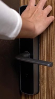 woman pressing digital numbers to open wood door and go into the house. Unlocking blue numbers in electronic door guard. Girl is opening the smart security door of the room. Technology home