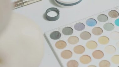 genç bir kızın eli bir palet bir fırça ile bir göz farı alır ve çok fazla eziyor, bir kadın kozmetik, bir güzellik konsepti ve bir gençlik yaşam tarzı ile makyaj yapar