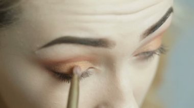 ayna önünde makyaj yapan güzel kız, stüdyo arka plan üzerinde bir fırça ile gölgeler ile göz kapağı boyama genç kadın, kozmetik ve güzellik kavramı