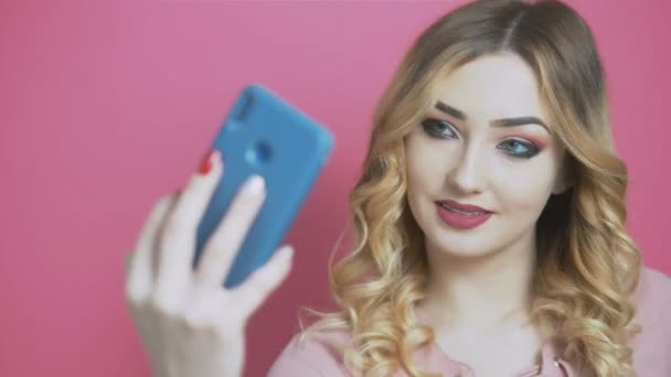 年轻美丽的女孩在社交网络上摆出一副自私自利的架势 一个少年手里拿着手机 对着摄像机笑着 对着年轻人的生活方式 一代和科技的概念 — 图库视频影像