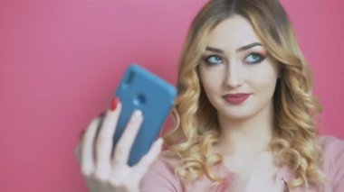 Bir sosyal ağ için selfie çeken genç ve güzel bir kız, elinde bir telefonla kameraya gülümsüyor, gençlik yaşam tarzı, nesil ve teknoloji kavramı
