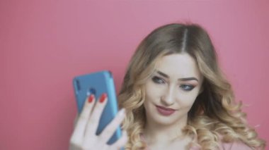 Bir sosyal ağ için selfie çeken genç ve güzel bir kız, elinde bir telefonla kameraya gülümsüyor, gençlik yaşam tarzı, nesil ve teknoloji kavramı