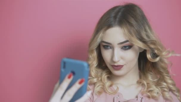 年轻美丽的女孩在社交网络上摆出一副自私自利的架势 一个少年手里拿着手机 对着摄像机笑着 对着年轻人的生活方式 一代和科技的概念 — 图库视频影像