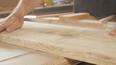 Genç adam ahşap bir tahtayı dairesel testere bıçağıyla kesiyor, ahşap işçiliği için profesyonel bir aletle bir atölye kuruyor, inşaat parçaları üretiminde kullanılan bir inşaat süreci kavramı.