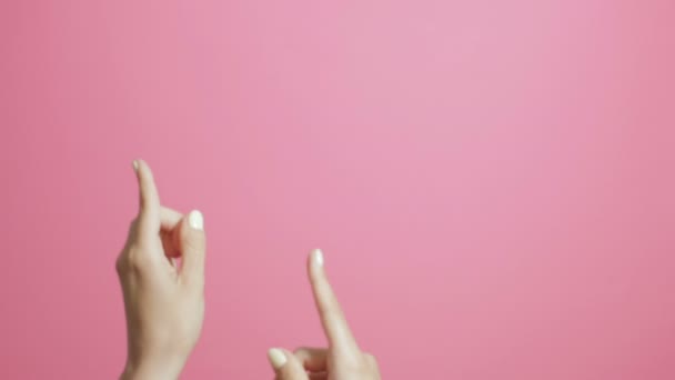 女の子の指が上を向いて 女の子は積極的にピンクのスタジオの背景にジェスチャーを宣伝します — ストック動画