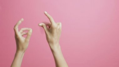 pembe bir stüdyo arka plan üzerinde sevinçle beat parmakları şıklatma genç bir kadının elleri