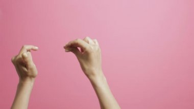 pembe bir stüdyo arka plan üzerinde sevinçle beat parmakları şıklatma genç bir kadının elleri