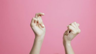 pembe bir stüdyo arka plan üzerinde sevinçle beat parmakları şıklatma genç bir kadının elleri