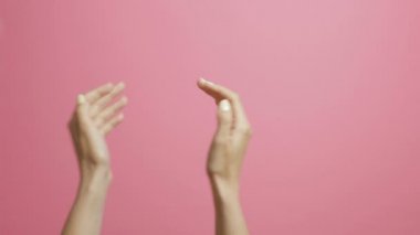 pembe bir stüdyo arka plan üzerinde sevinçle alkışlayan genç bir kadının elleri