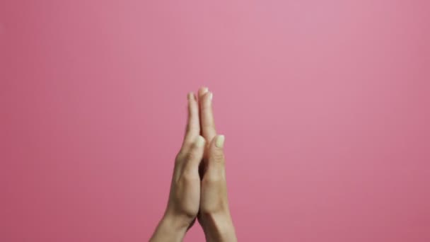 一个年轻女子的手拍手与喜悦在粉红色的工作室背景 — 图库视频影像