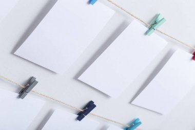 beyaz arka plan üzerinde bir iplik üzerinde renkli clothespins asılı boş beyaz kartlar, bir fotoğraf kolaj için bir şablon, anılar kavramı ve bir fotoğraf endüstrisi