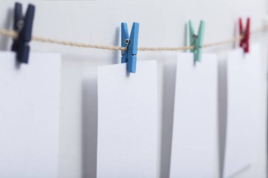 beyaz arka plan üzerinde bir iplik üzerinde renkli clothespins asılı boş beyaz kartlar, bir fotoğraf kolaj için bir şablon, anılar kavramı ve bir fotoğraf endüstrisi
