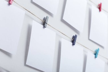 beyaz arka plan üzerinde bir iplik üzerinde renkli clothespins asılı boş beyaz kartlar, bir fotoğraf kolaj için bir şablon, anılar kavramı ve bir fotoğraf endüstrisi