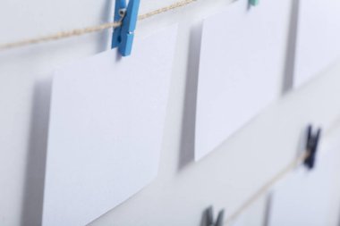 beyaz arka plan üzerinde bir iplik üzerinde renkli clothespins asılı boş beyaz kartlar, bir fotoğraf kolaj için bir şablon, anılar kavramı ve bir fotoğraf endüstrisi