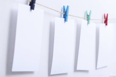 beyaz arka plan üzerinde bir iplik üzerinde renkli clothespins asılı boş beyaz kartlar, bir fotoğraf kolaj için bir şablon, anılar kavramı ve bir fotoğraf endüstrisi
