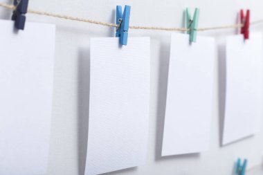 beyaz arka plan üzerinde bir iplik üzerinde renkli clothespins asılı boş beyaz kartlar, bir fotoğraf kolaj için bir şablon, anılar kavramı ve bir fotoğraf endüstrisi