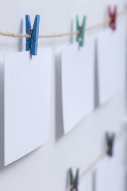 beyaz arka plan üzerinde bir iplik üzerinde renkli clothespins asılı boş beyaz kartlar, bir fotoğraf kolaj için bir şablon, anılar kavramı ve bir fotoğraf endüstrisi