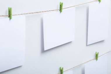 beyaz arka plan üzerinde bir iplik üzerinde renkli clothespins asılı boş beyaz kartlar, bir fotoğraf kolaj için bir şablon, anılar kavramı ve bir fotoğraf endüstrisi
