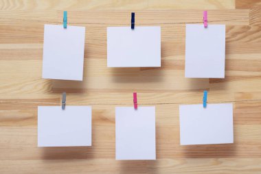 ahşap tahtanın arka planında keten halat üzerine renkli kelepçe ile bağlı boş kağıt kartlar, görüntü veya metin için boş şablonlar, konsept fotoğraf dekoru