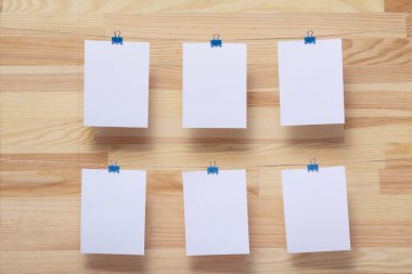 ahşap tahtanın arka planında keten halat üzerine renkli kelepçe ile bağlı boş kağıt kartlar, görüntü veya metin için boş şablonlar, konsept fotoğraf dekoru