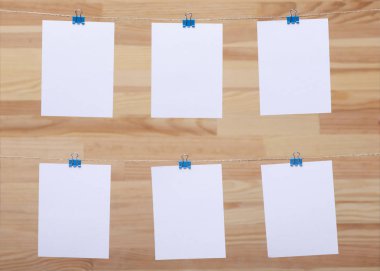 ahşap tahtanın arka planında keten halat üzerine renkli kelepçe ile bağlı boş kağıt kartlar, görüntü veya metin için boş şablonlar, konsept fotoğraf dekoru