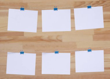 ahşap tahtanın arka planında keten halat üzerine renkli kelepçe ile bağlı boş kağıt kartlar, görüntü veya metin için boş şablonlar, konsept fotoğraf dekoru