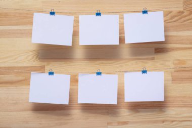 ahşap tahtanın arka planında keten halat üzerine renkli kelepçe ile bağlı boş kağıt kartlar, görüntü veya metin için boş şablonlar, konsept fotoğraf dekoru