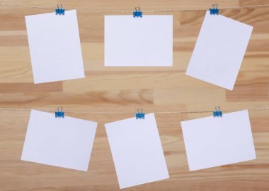 ahşap tahtanın arka planında keten halat üzerine renkli kelepçe ile bağlı boş kağıt kartlar, görüntü veya metin için boş şablonlar, konsept fotoğraf dekoru