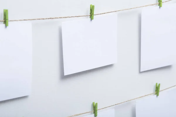 Tomma vita kort hängande på färgade klädnypor på en tråd på en vit bakgrund, en mall för ett fotokollage, ett koncept av minnen och en bild industrin — Stockfoto