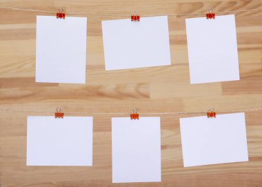 ahşap tahtanın arka planında keten halat üzerine renkli kelepçe ile bağlı boş kağıt kartlar, görüntü veya metin için boş şablonlar, konsept fotoğraf dekoru