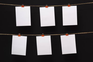 siyah bir arka plan üzerinde keten halat üzerinde renkli clothespins ile bağlı boş kağıt kartları, boş şablonlar konsept ofis ve fotoğraf endüstrisi, dekor