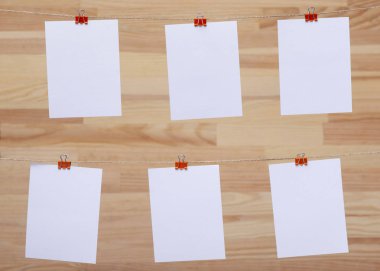 ahşap tahtanın arka planında keten halat üzerine renkli kelepçe ile bağlı boş kağıt kartlar, görüntü veya metin için boş şablonlar, konsept fotoğraf dekoru