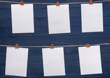 bulanıklık ahşap mavi tahta arka planda keten halat üzerinde renkli klipler ile bağlı boş kağıt kartları, görüntü veya metin için boş şablonlar, konsept fotoğraf duvarı