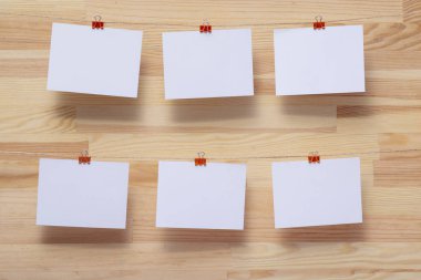 ahşap tahtanın arka planında keten halat üzerine renkli kelepçe ile bağlı boş kağıt kartlar, görüntü veya metin için boş şablonlar, konsept fotoğraf dekoru