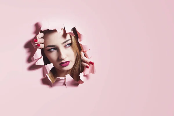 Портрет моди молодої жінки, що розриває дірку в рожевому картонному папері, обличчя дівчини з макіяжем, творча концепція свобода в моді, молодіжний спосіб життя, порожнє рекламне місце — стокове фото