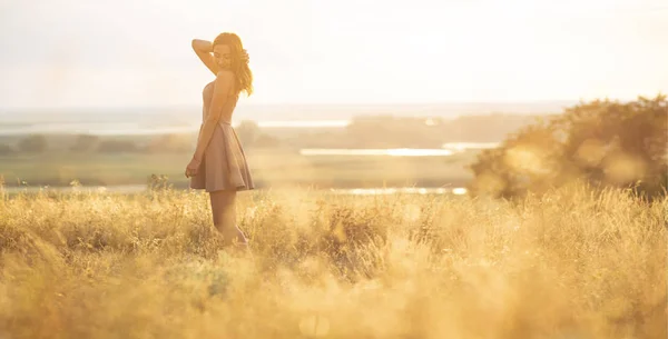 Мечтательная девушка в поле на закате, молодая женщина в тумане от солнца наслаждаясь природой, романтический стиль — стоковое фото
